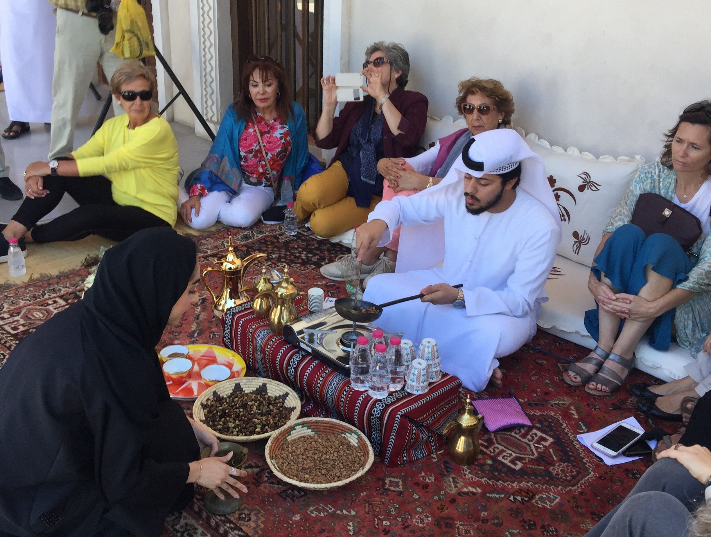 Turistas participando en una experiencia cultural con café árabe y dátiles en Sharjah durante el tour desde Dubái con Passion Dubai Tours