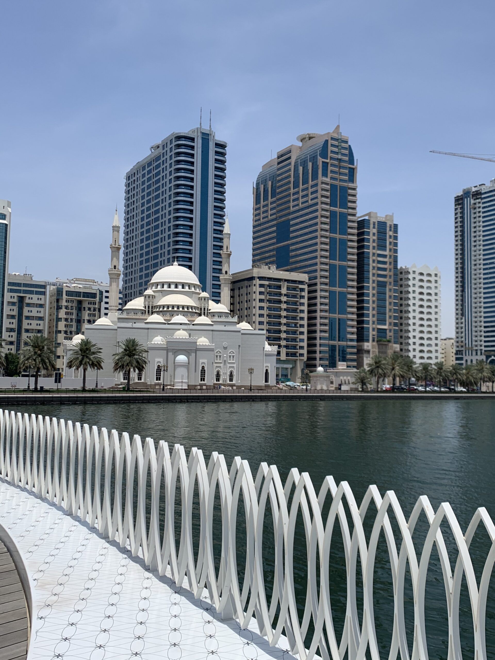 Mezquita Al Noor frente a la laguna Khalid en Sharjah con rascacielos modernos al fondo durante el tour cultural desde Dubái con Passion Dubai Tours