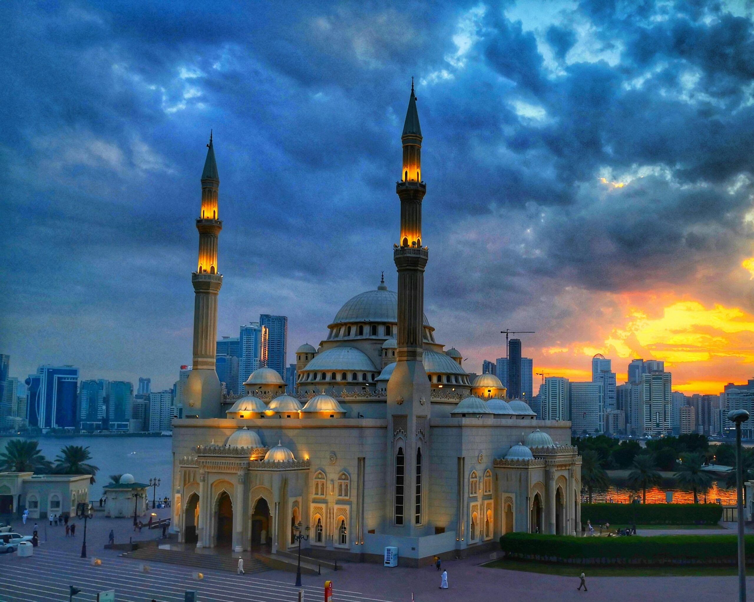 Gran Mezquita de Sharjah al atardecer con el skyline de la ciudad al fondo durante el tour cultural desde Dubái con Passion Dubai Tours