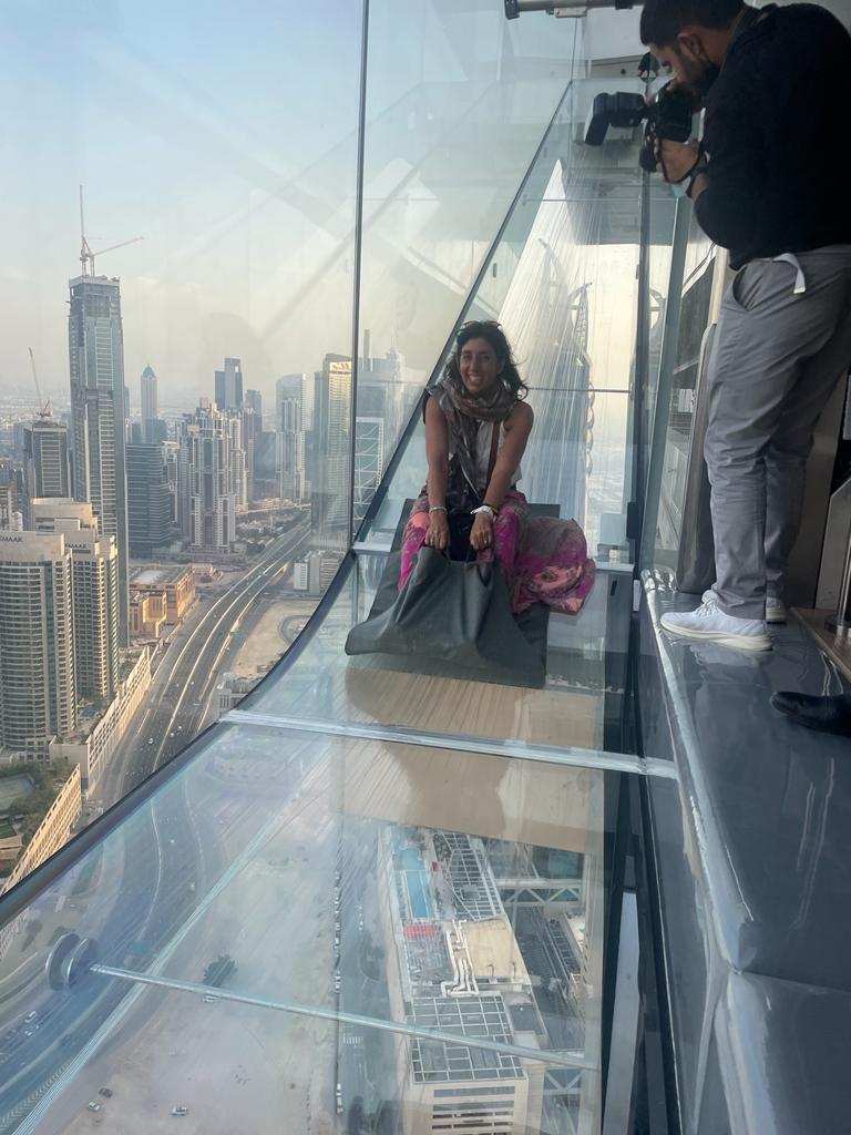 Turista disfrutando del Sky Views Slide en Dubái con vistas panorámicas a la ciudad