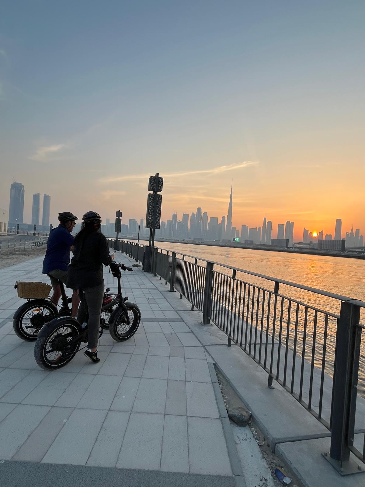 Pareja en tour en bicicleta eléctrica en Dubái con vistas al Burj Khalifa al atardecer