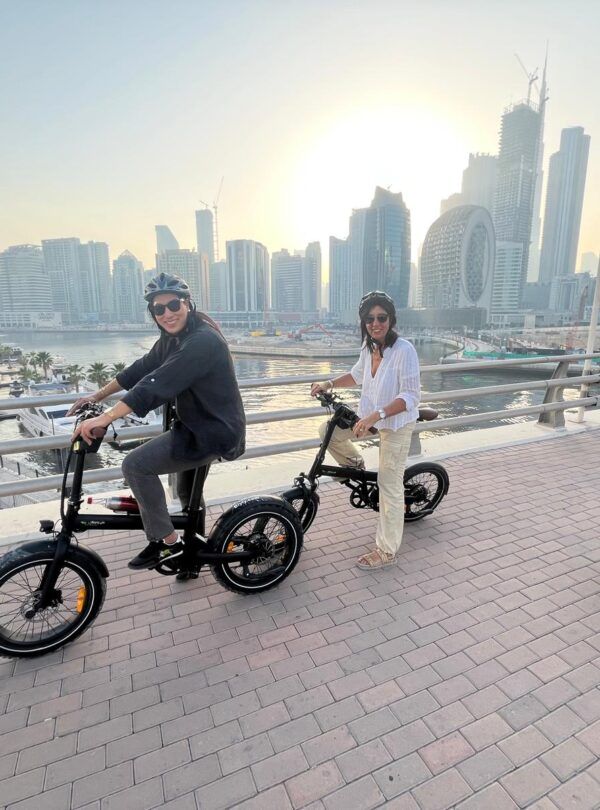 Turistas en el tour en bicicleta eléctrica por la Marina de Dubái con el skyline de fondo