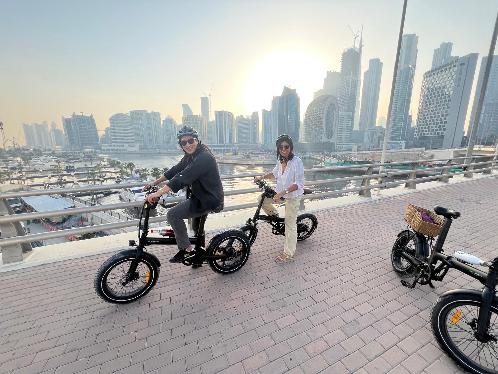 Turistas en el tour en bicicleta eléctrica por la Marina de Dubái con el skyline de fondo